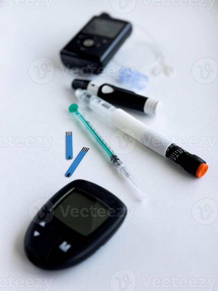 Diabetes management tools, glucose meter, insulin pen, and pump on white surface photo