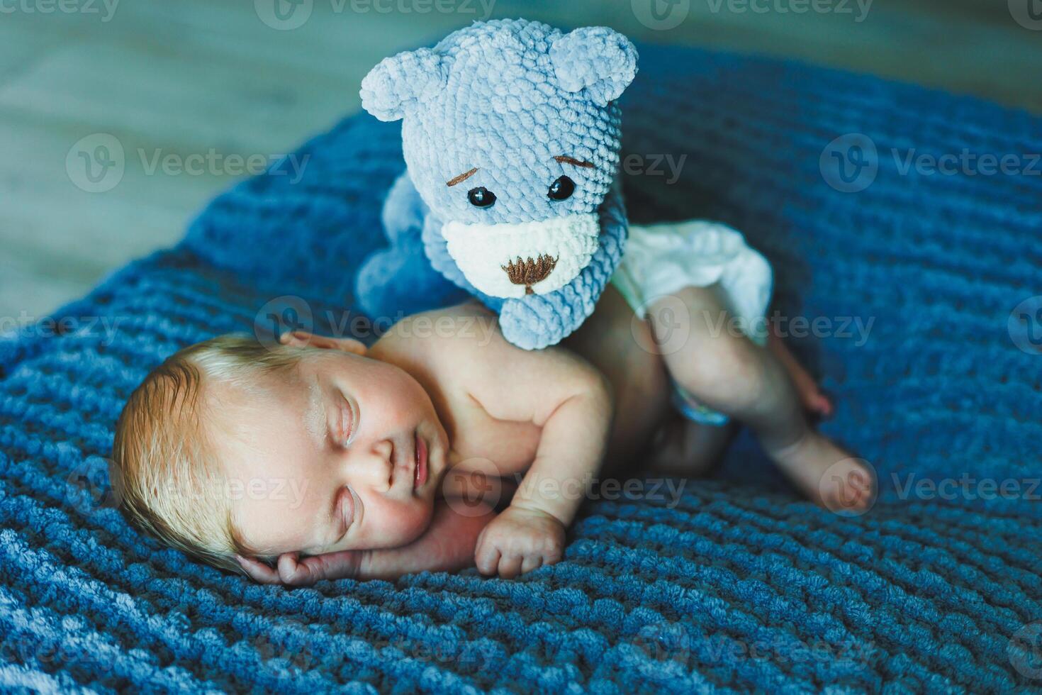 A newborn baby sleeps with a knitted teddy bear. Children's knitted toys. Baby sleep photo