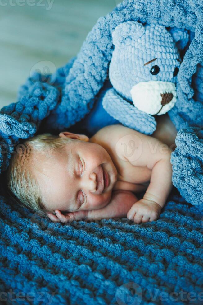 A newborn baby sleeps with a knitted teddy bear. Children's knitted toys. Baby sleep photo