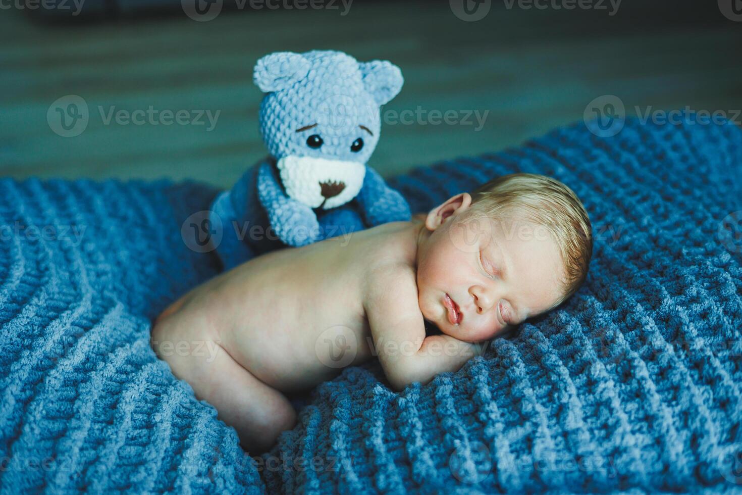 A newborn baby sleeps with a knitted teddy bear. Children's knitted toys. Baby sleep photo