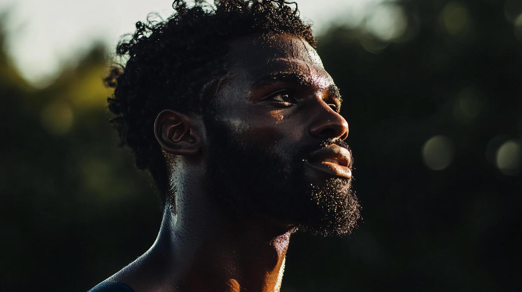 Man with a beard and dreadlocks is sweating in the sun. He is looking up at the sky photo