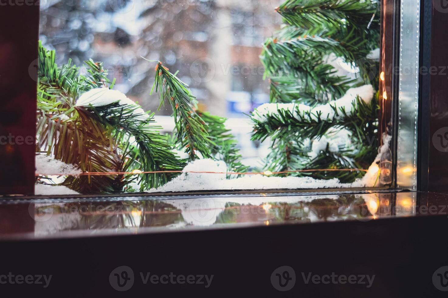 a Christmas window sill on which you can put something. there is a fir tree garland and snow outside the window. High quality photo