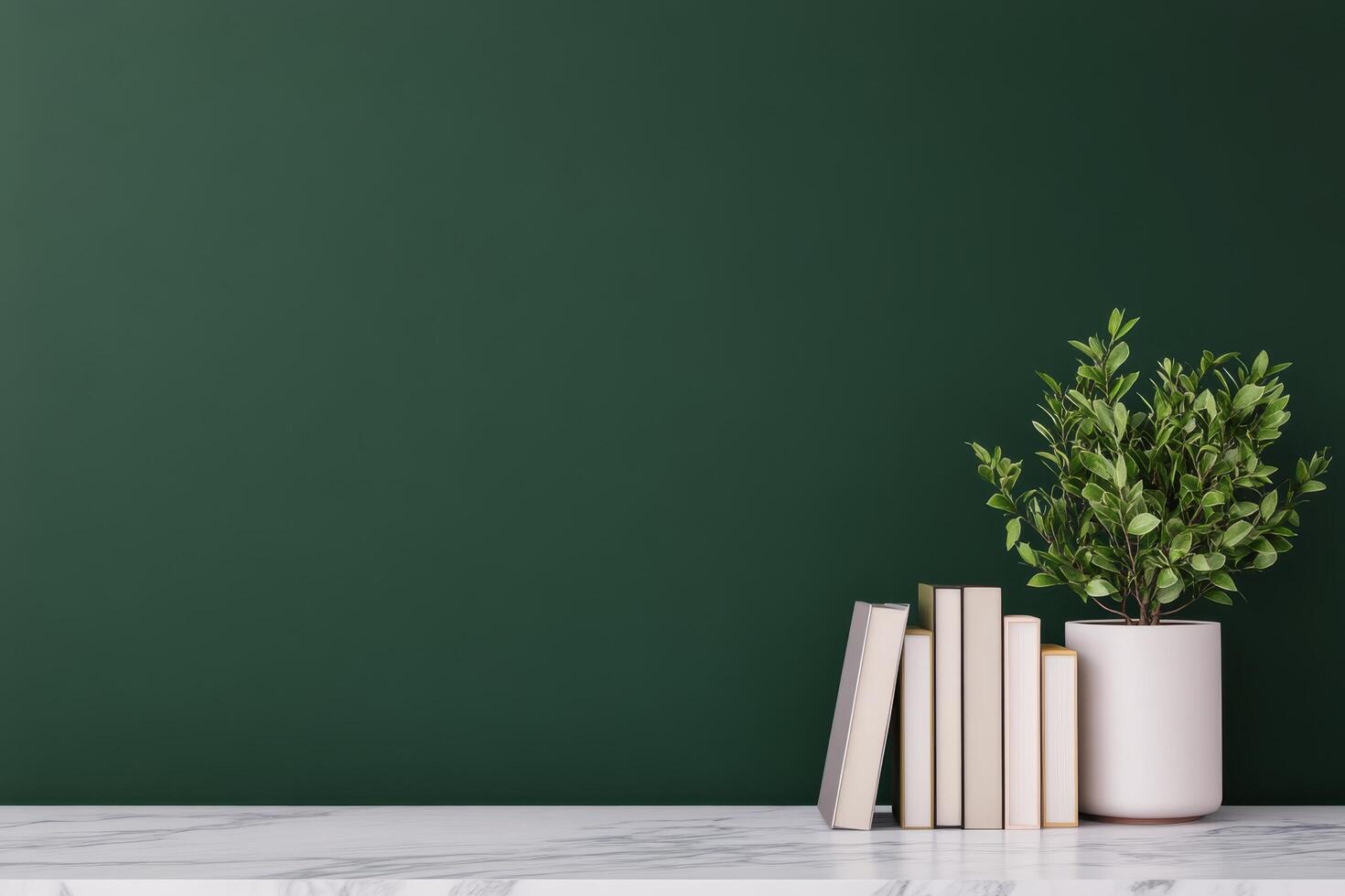 Elegant desk setup with books and greenery beside dark green wall photo