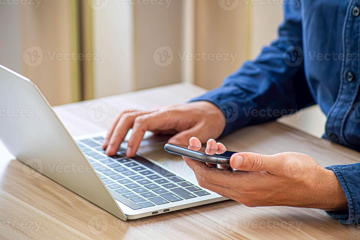 Woman working online on the keyboard of her laptop computer While holding the phone photo