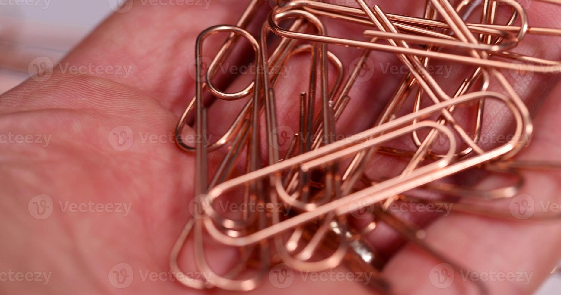 large-sized copper paper clips lie on white blank paper photo