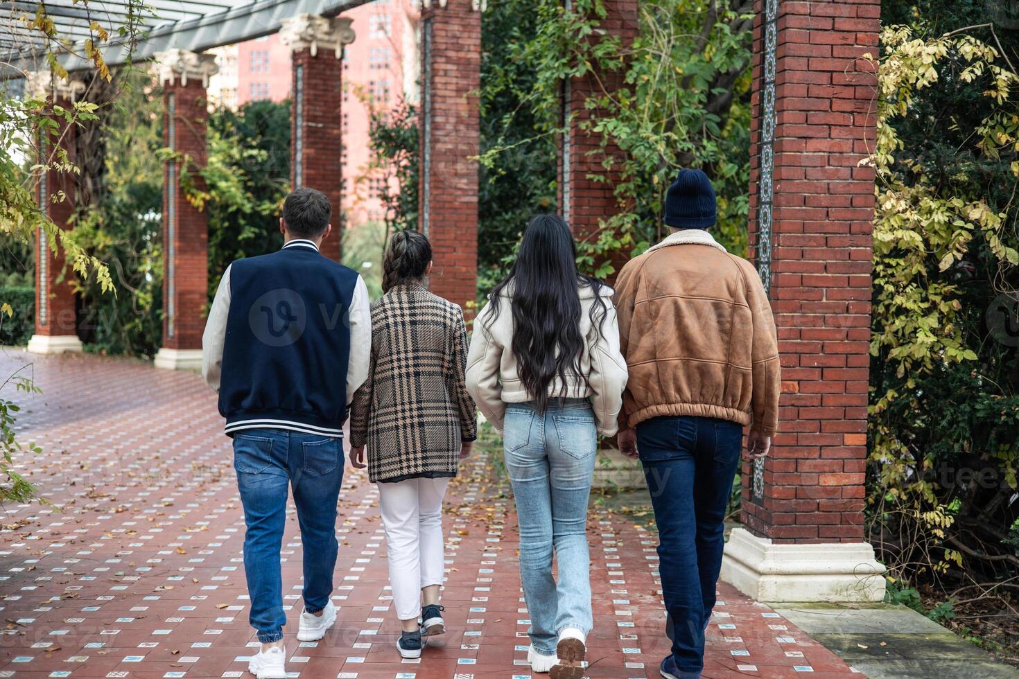 group of four young friends walking backwards outdoors photo