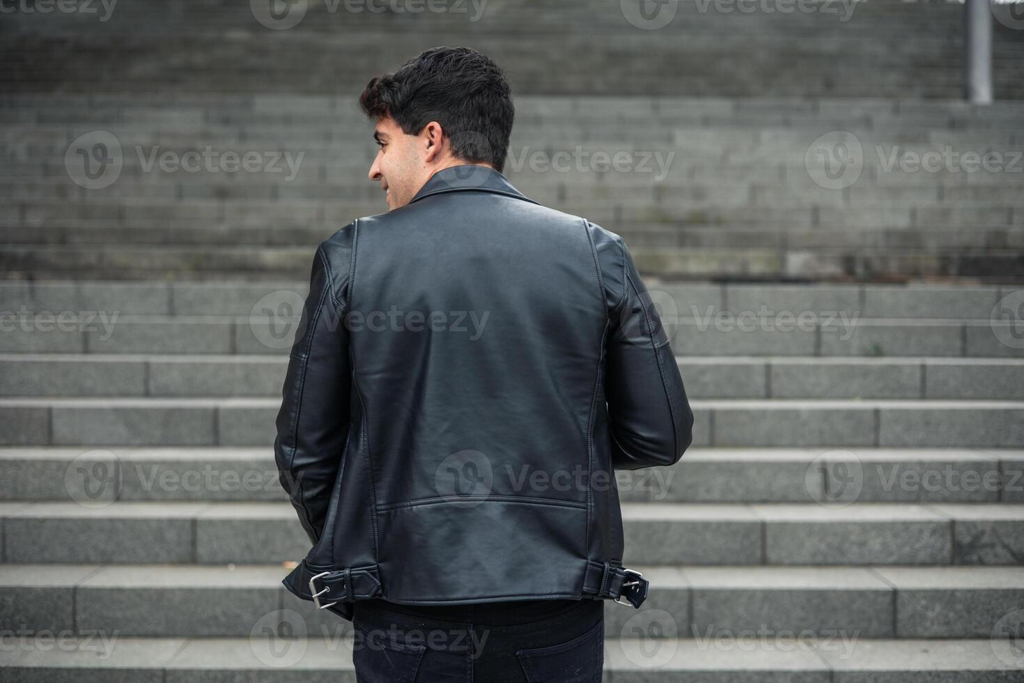 young man from behind in leather jacket climbing stairs photo