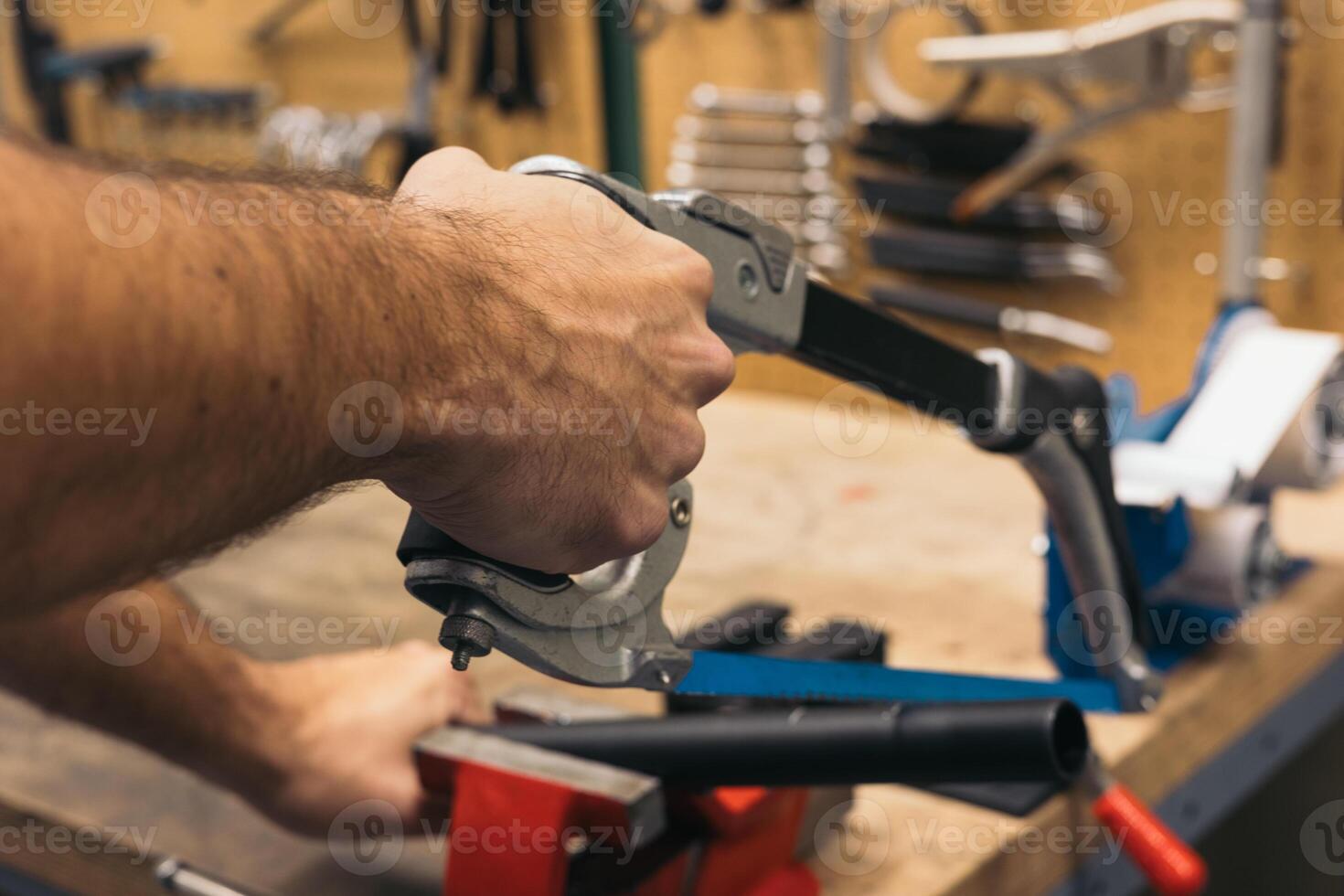 closeup of hand cutting a pipe with saw in workshop photo