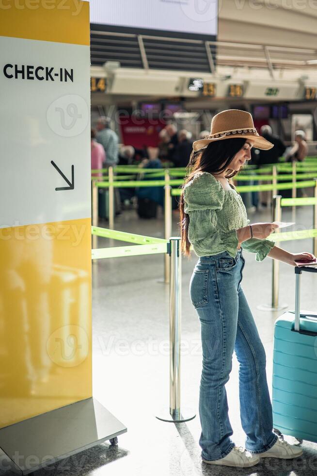 vertical portrait Latin woman waiting in the check-in line with boarding pass photo