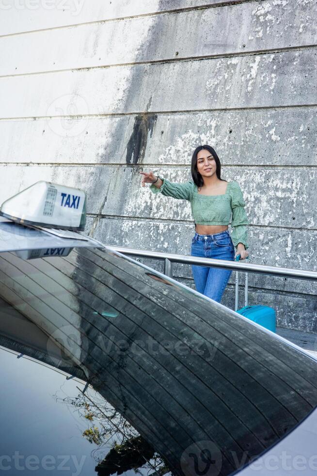 vertical portrait Latin woman trying to find a taxi upon arrival of her trip photo