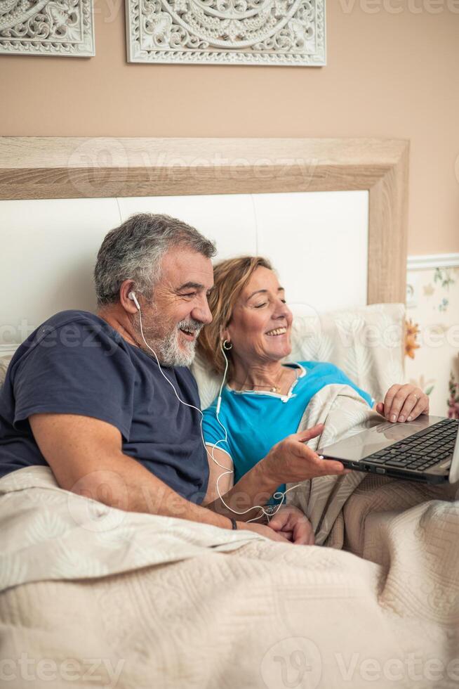 vertical portrait Digital Connection in Golden Years Senior Couple Enjoying Entertainment in Bed photo