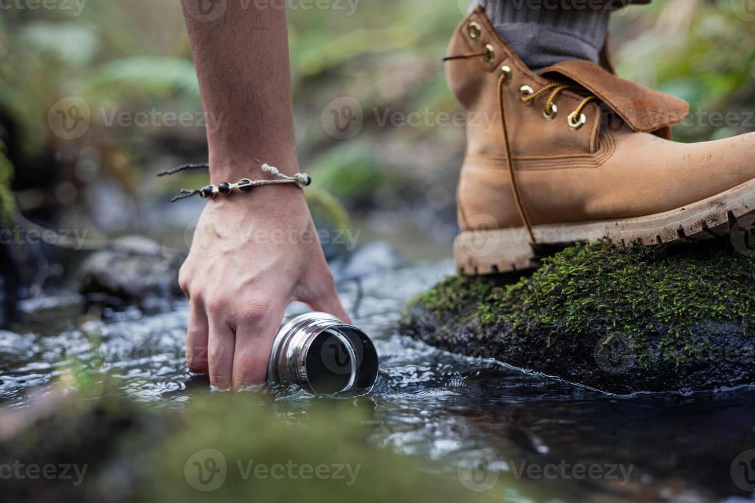 Hand and foot collecting water from river in forest photo