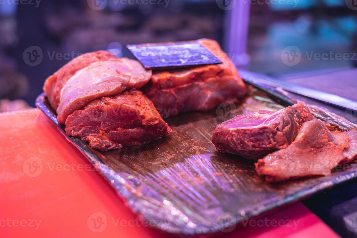 Closeup of Marinated Pork Loin Slices in Tray on Butcher Shop Counter photo