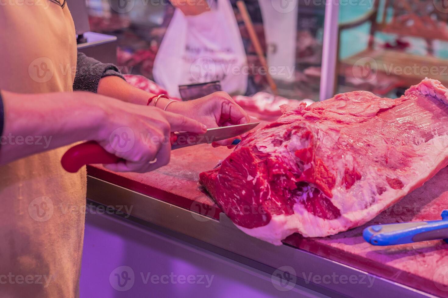 Closeup of Female Butcher's Hand Cutting Beef Steak with Knife photo