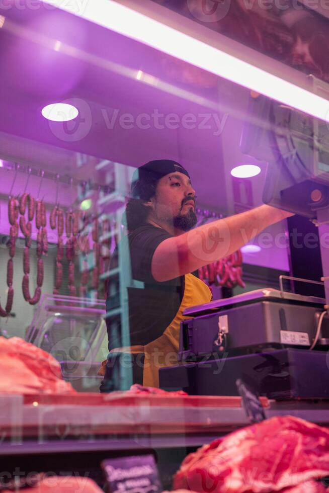 vertical portrait Butcher Weighing Fresh Cuts in His Shop photo