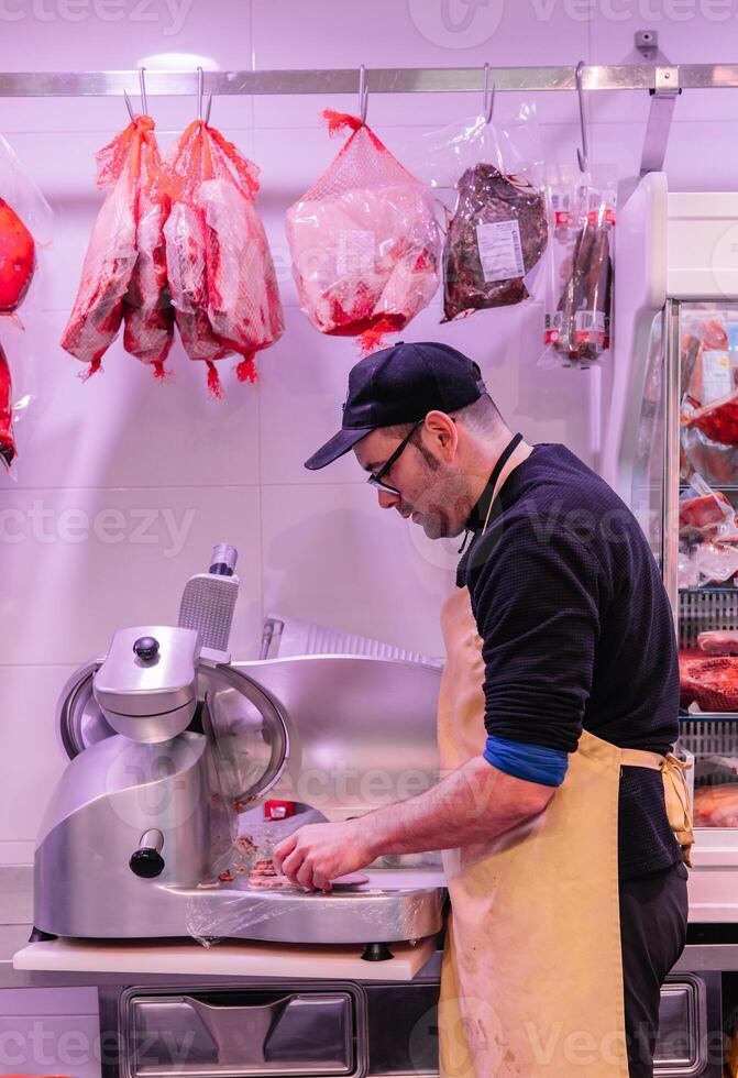 vertical portrait Precision at Work Butcher Operating Meat Cutting Machine photo