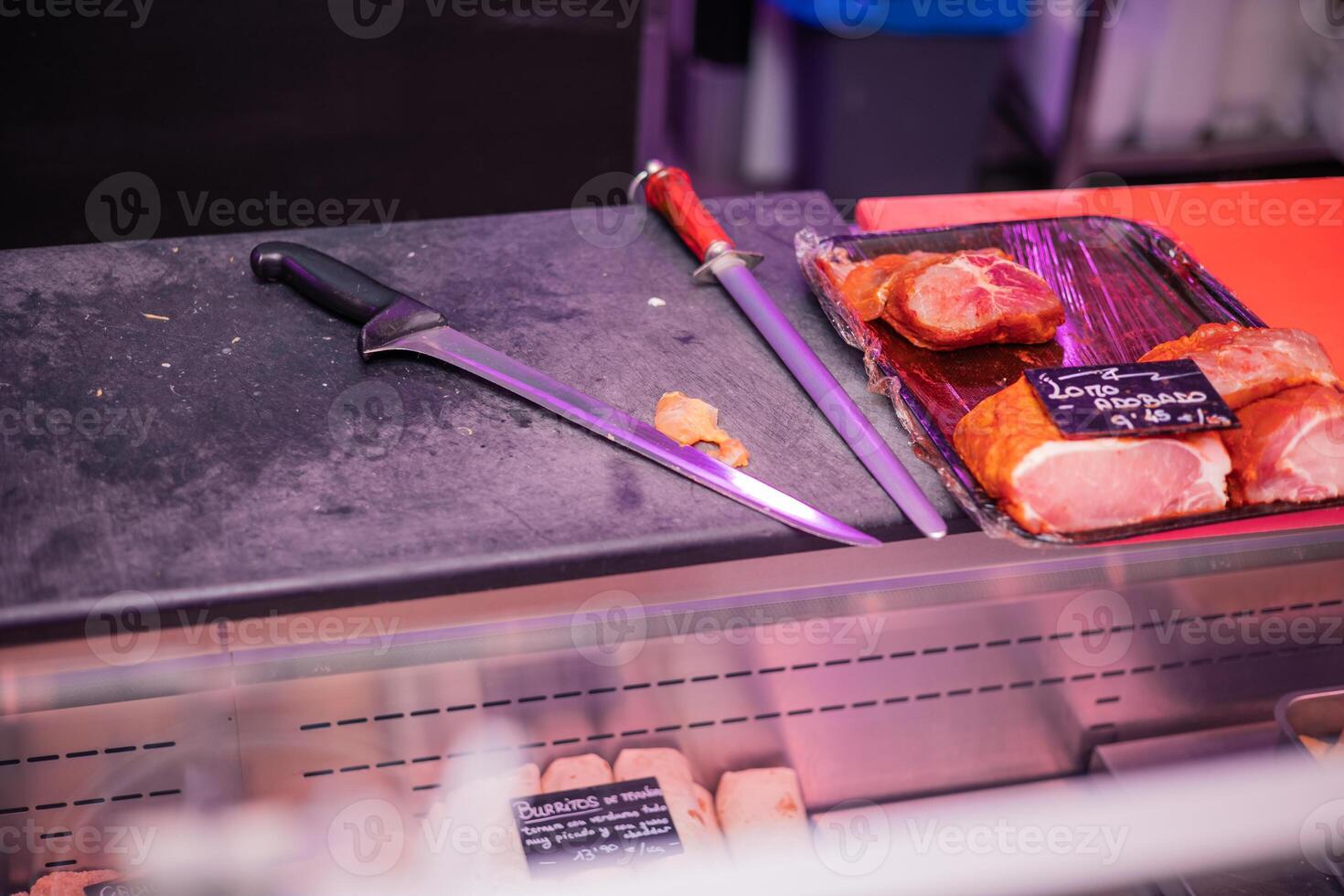 Butcher Knife and Knife Sharpener on Meat Cutting Board with Marinated Pork Loin Tray photo