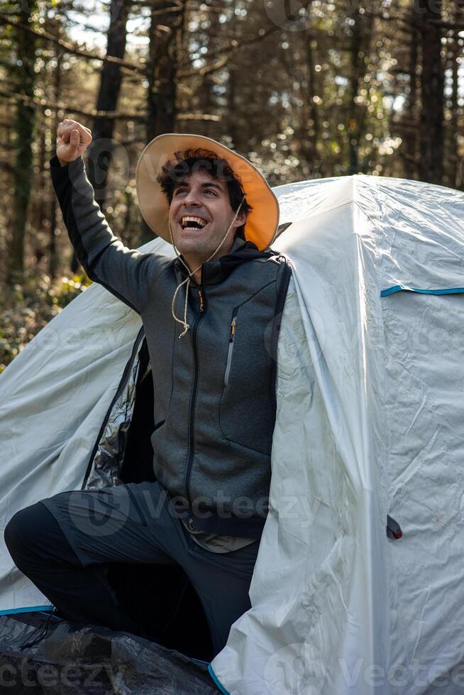 vertical portrait Camper Stretching at Sunrise from Tent Door in Summer photo