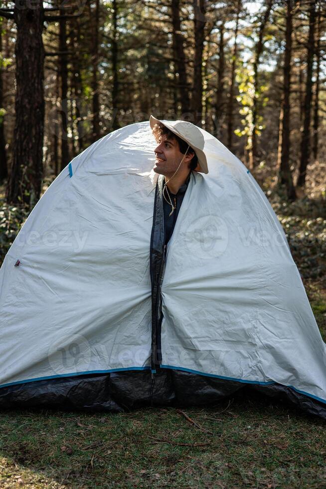 vertical portrait Smiling Explorer Camper Peeking from camping Tent at Summer Morning photo