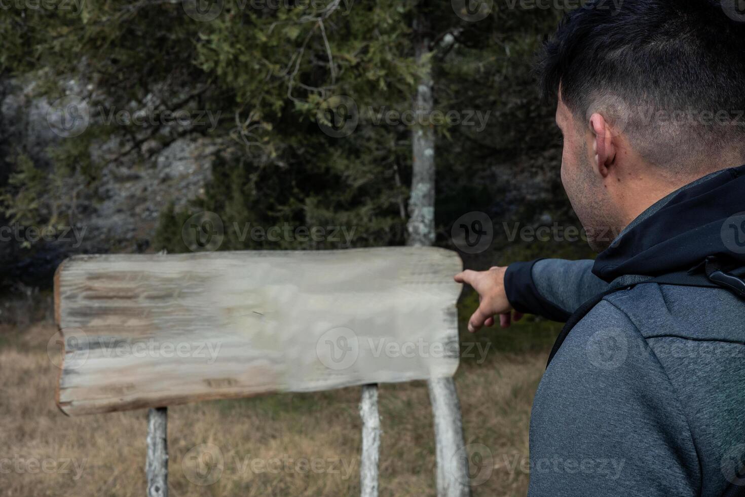 closeup Hiker Pointing Finger at Information Sign in Forest photo