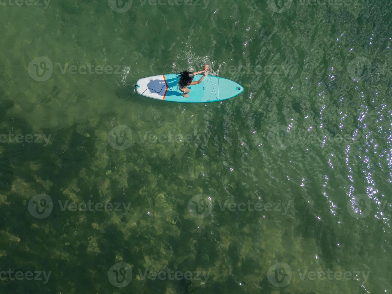 cenital copyspace above view Young Latin paddleboarding with board in the sea on a sunny summer day photo