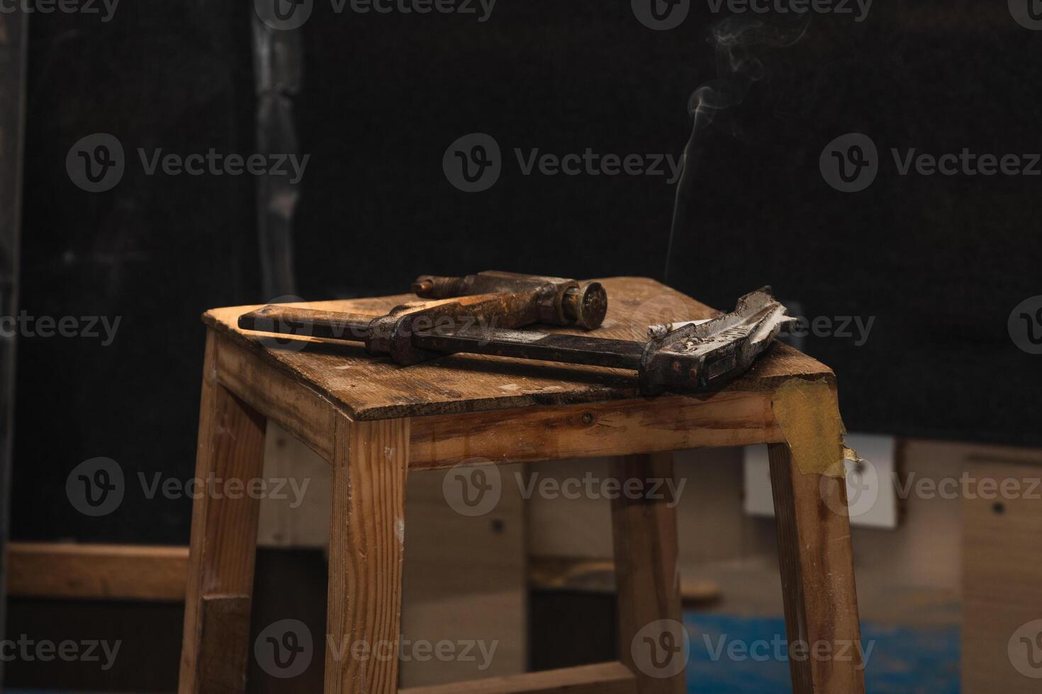 closeup Vintage Carpenter's Clamp with Smoking Cigarette on Wooden Workbench in Carpentry Workshop photo