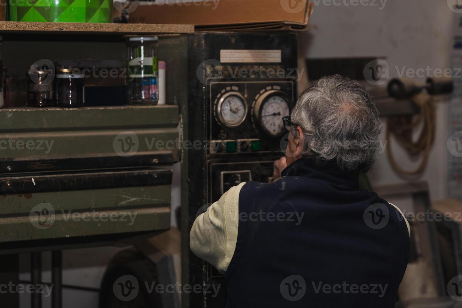 Elderly Carpenter Inspecting Vintage Wood Press Machine photo