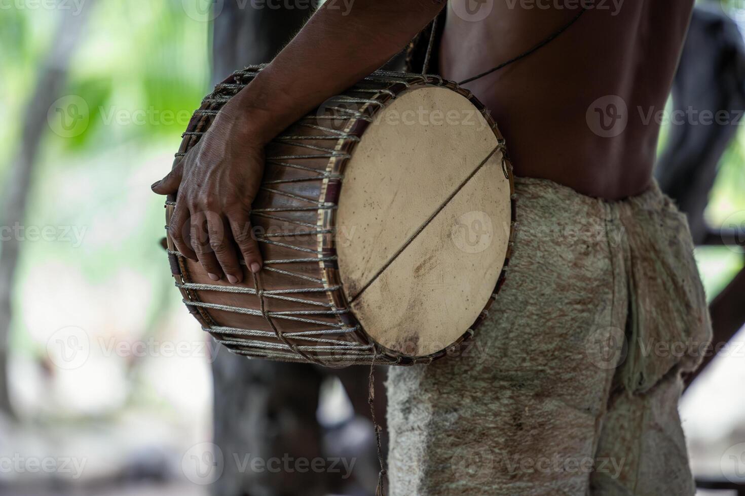 Closeup of Wayuri indigenous community member playing traditional drum in Ecuadorian Amazon photo