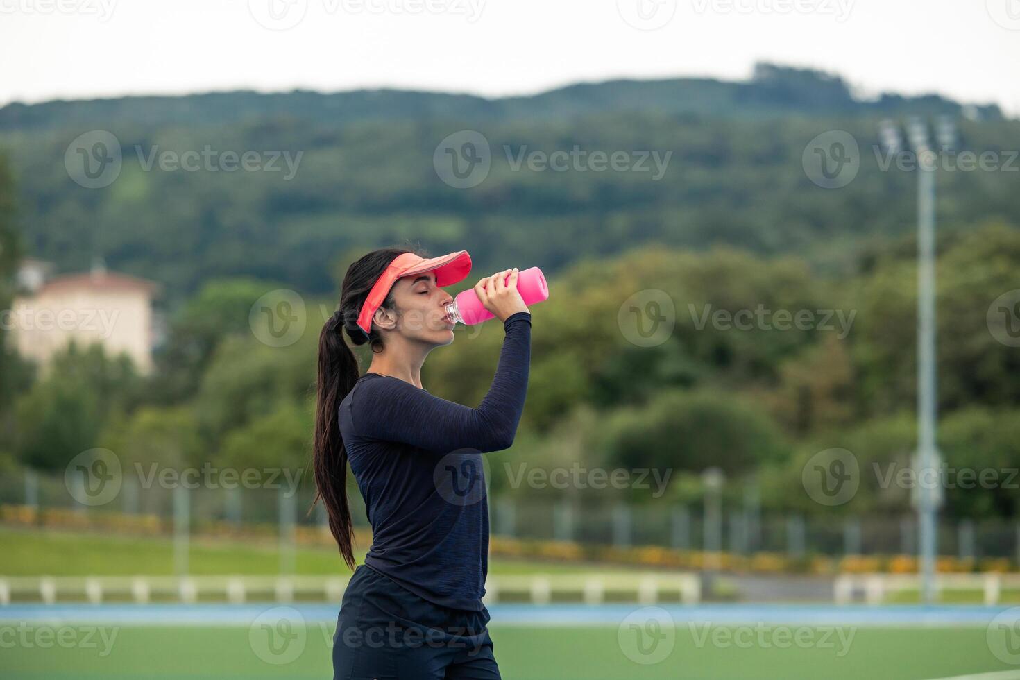 copyspace Latin Woman Runner Quenching Thirst with Pink Water Bottle after Intense Workout photo
