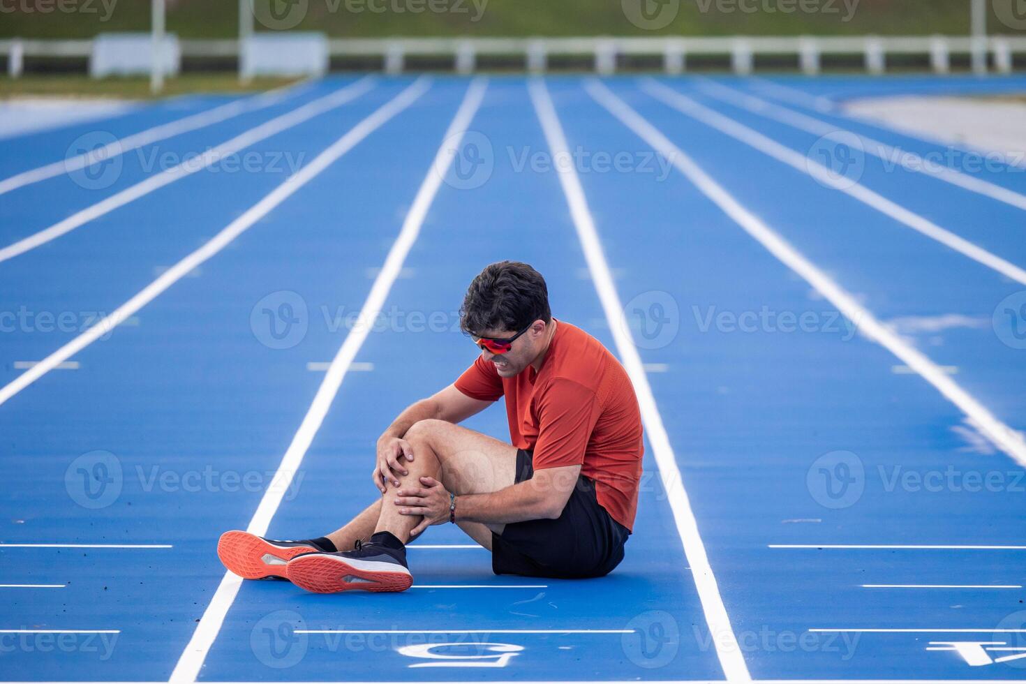 Injured Runner Clutches Leg in Pain on Athletic Track After Muscle Injury photo