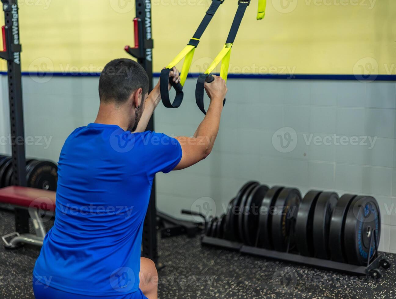athletic man doing leg workout with trx in gym photo