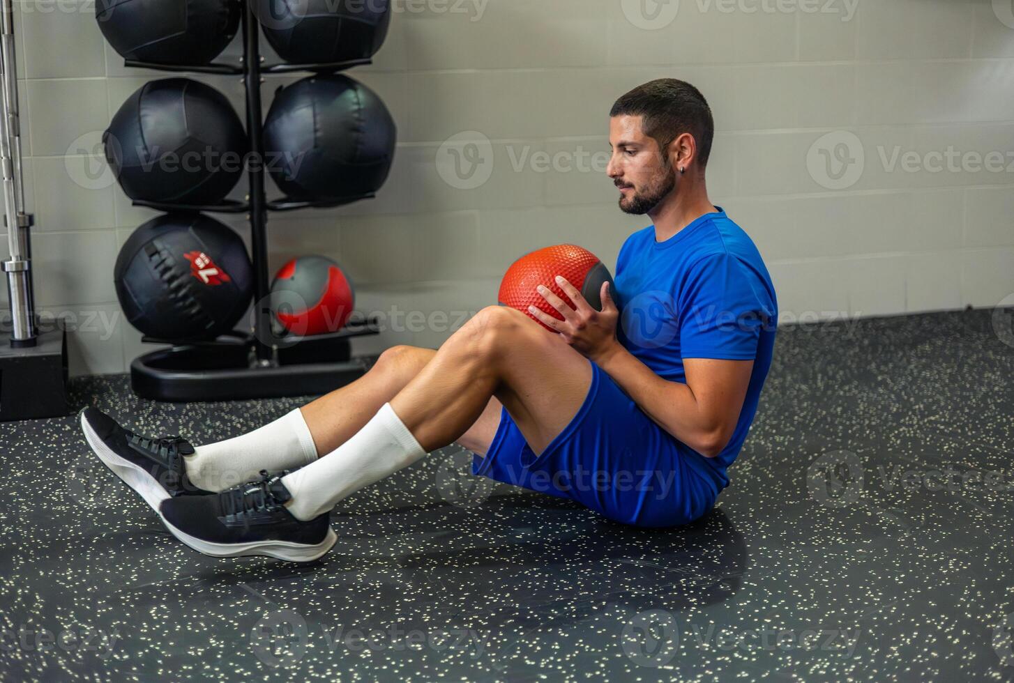 young athlete performs core exercises with medicine ball seated on gym floor photo