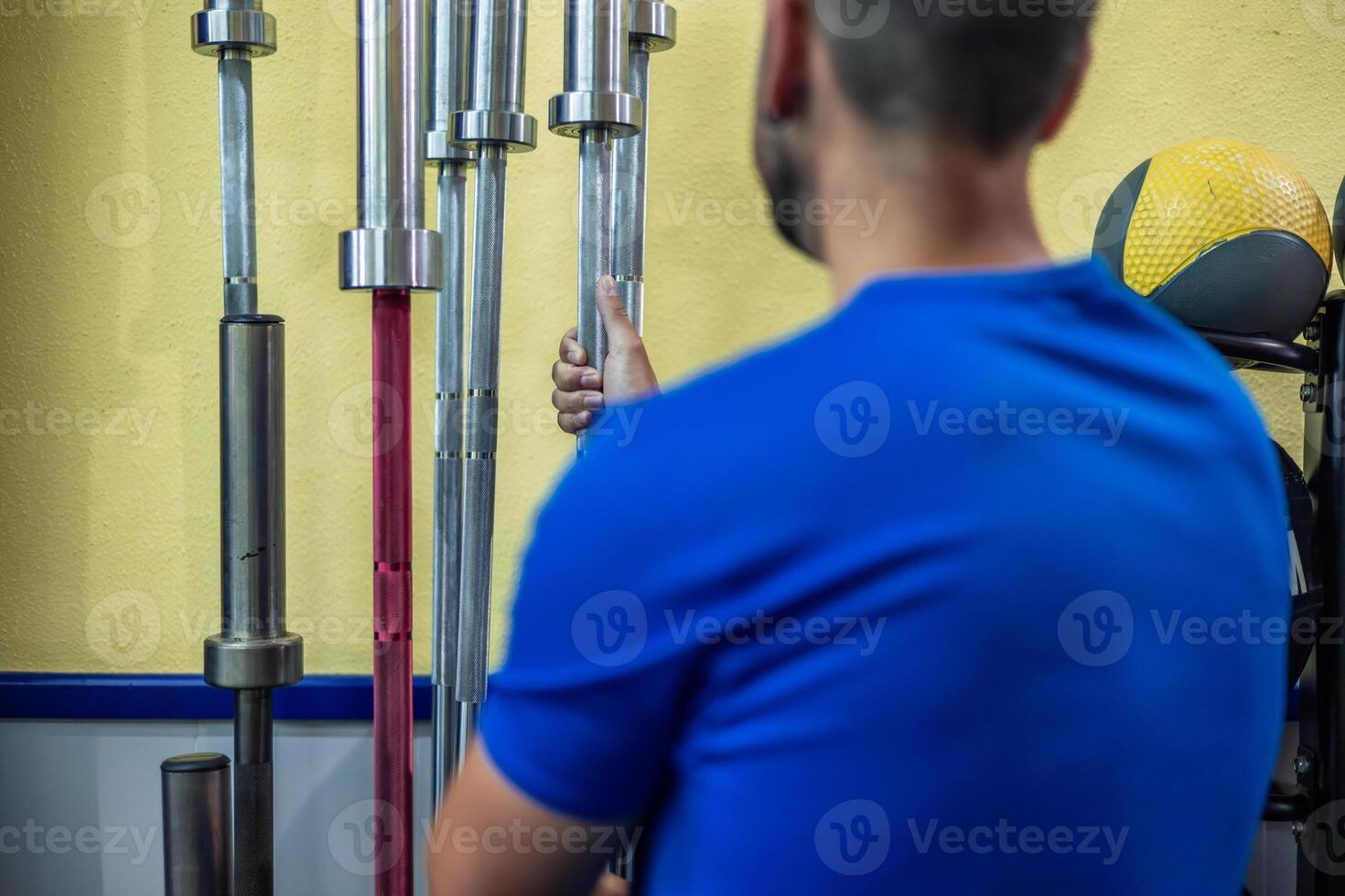 fitness athlete seen from behind grabbing Olympic barbell ready to bench press during gym training photo