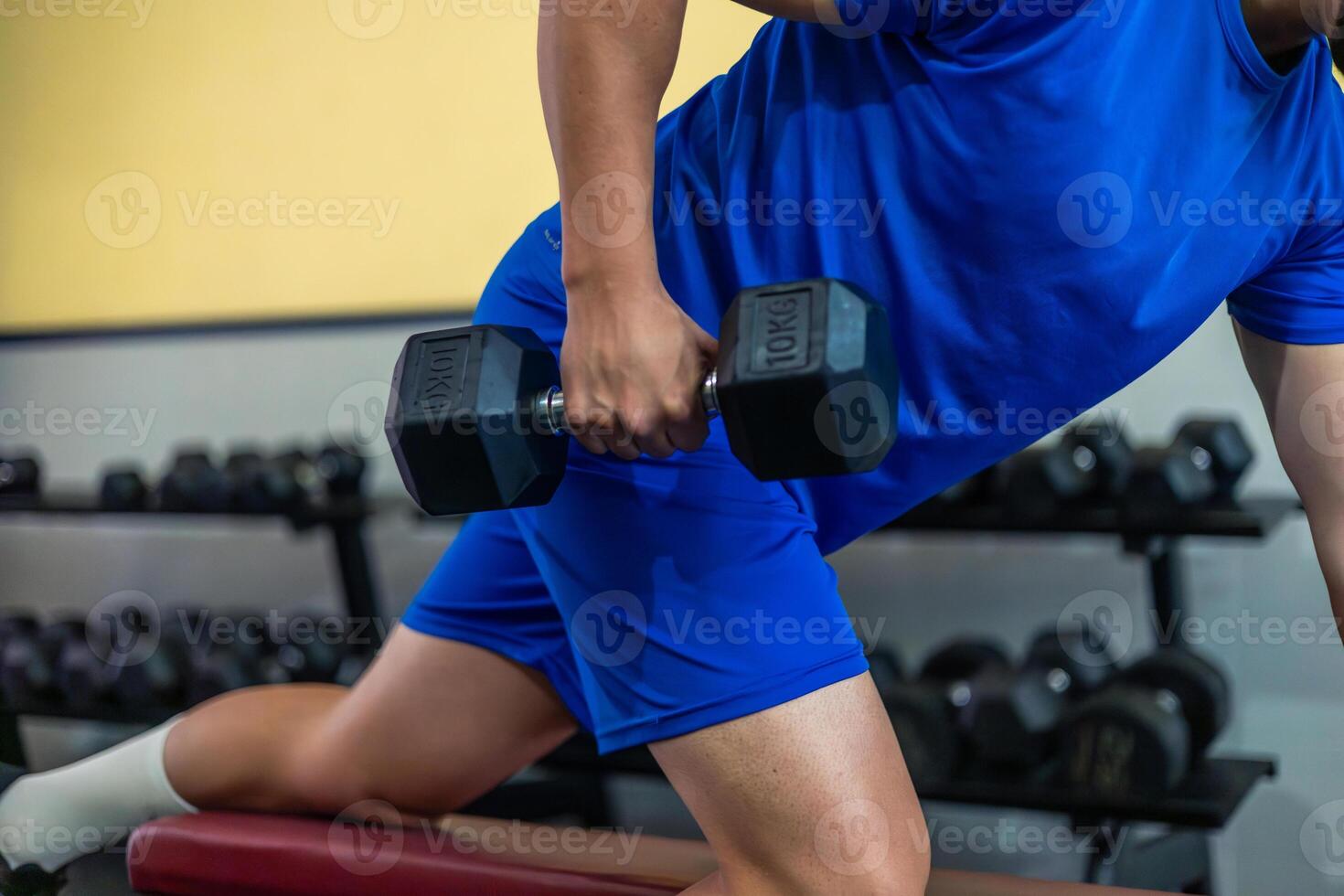 close-up of anonymous person doing triceps exercise with dumbbell on gym bench photo