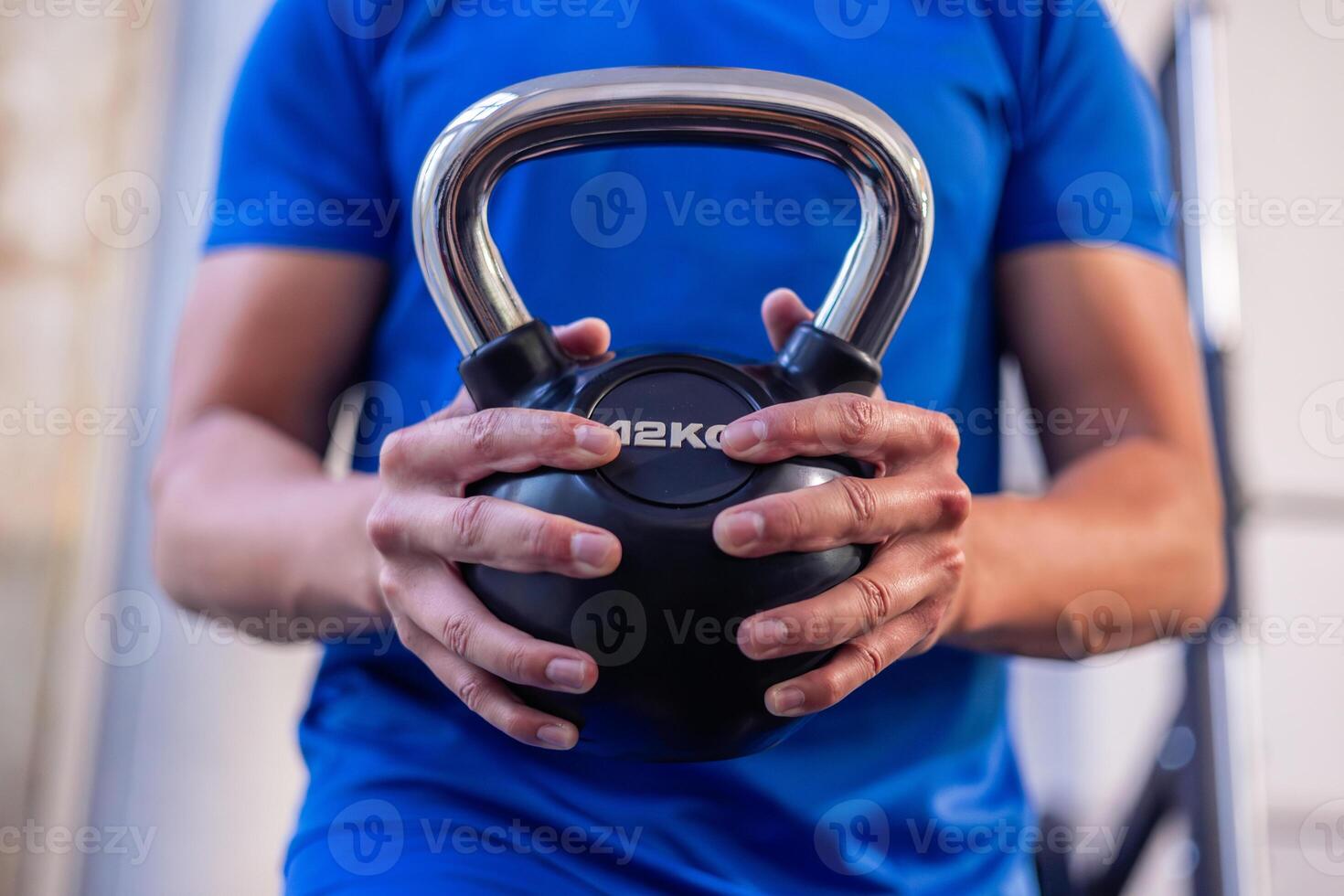 close-up of young athlete's hands holding 12 kg kettlebell during gym workout photo