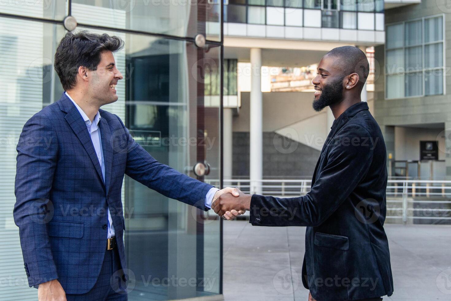 Multicultural businessmen shaking hands in city financial district photo