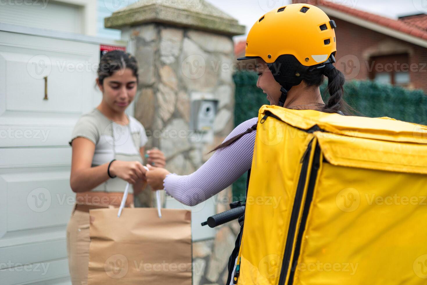 closeup Latin food delivery girl viewed from behind, delivering an order to customer at her doorstep photo