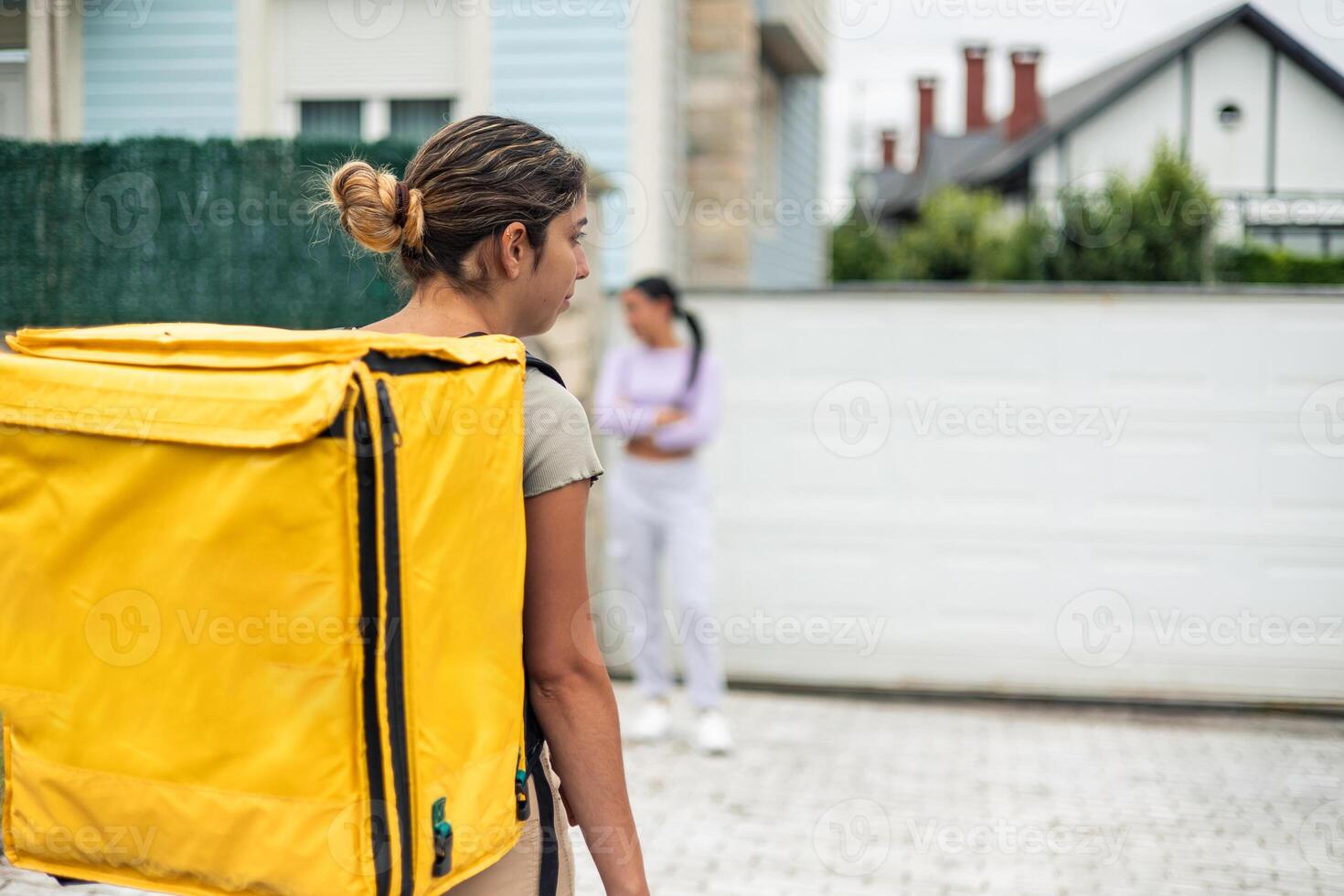copyspace worried food delivery girl with yellow backpack arriving at angry latin client's house photo