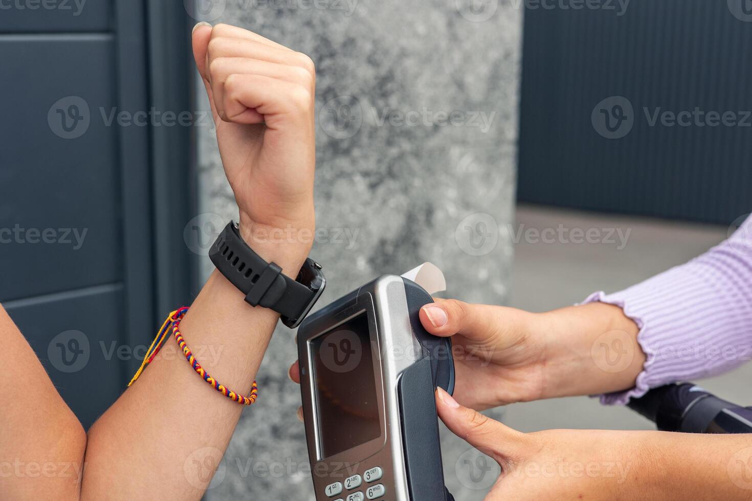 closeup Customers hand paying with smartwatch at card reader held by delivery woman photo