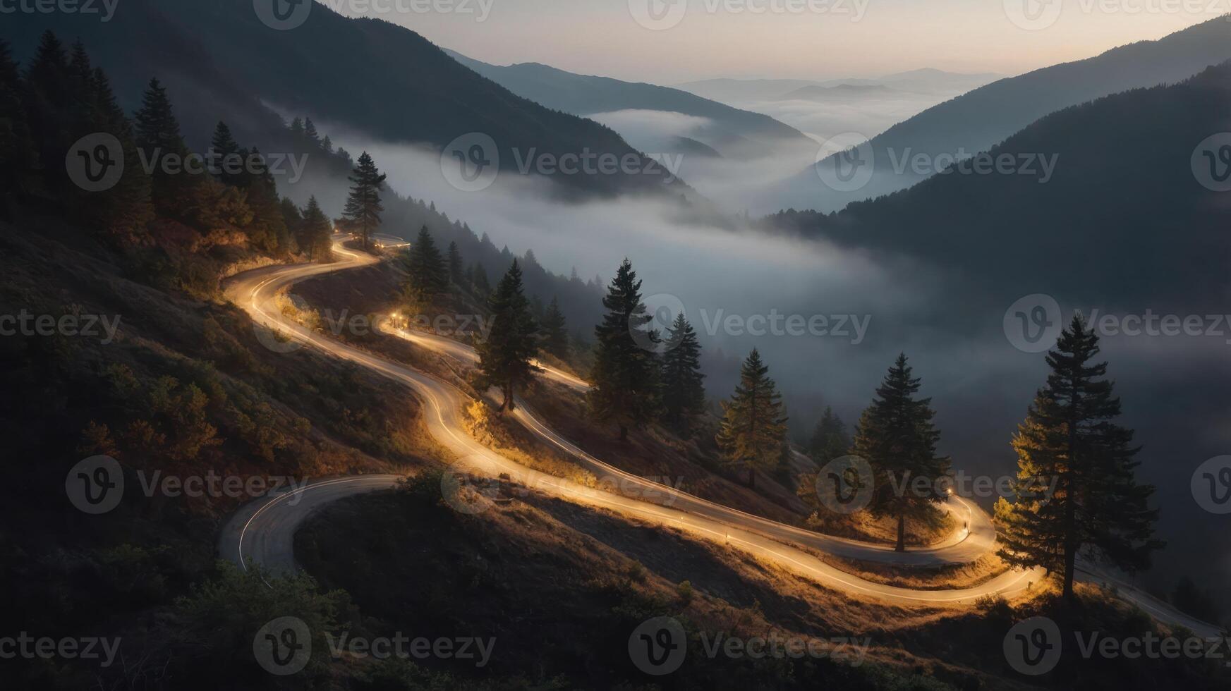A winding road through misty mountains at dusk, illuminated by vehicle lights. photo