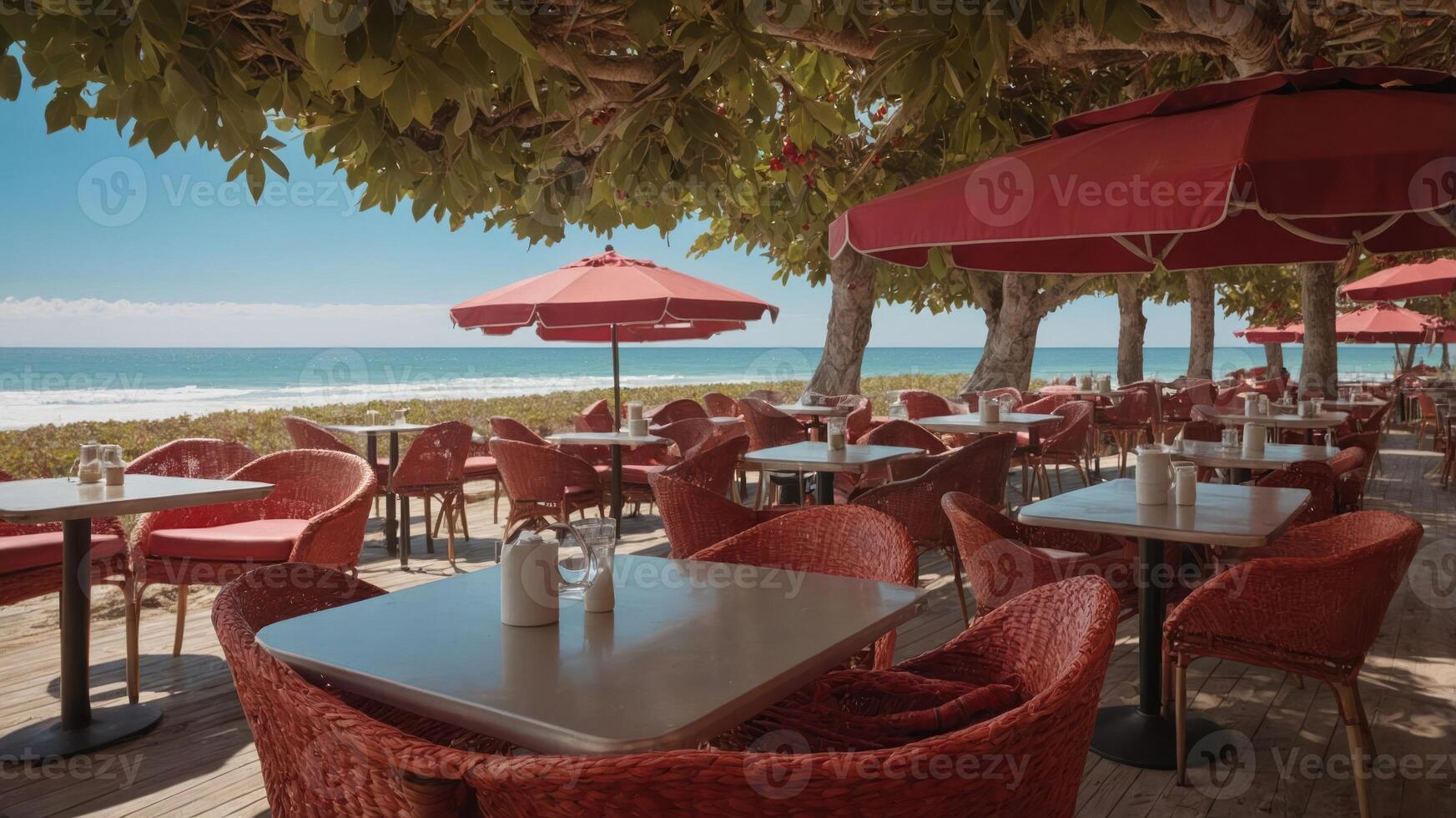 A seaside restaurant with outdoor seating, red umbrellas, and ocean views. photo