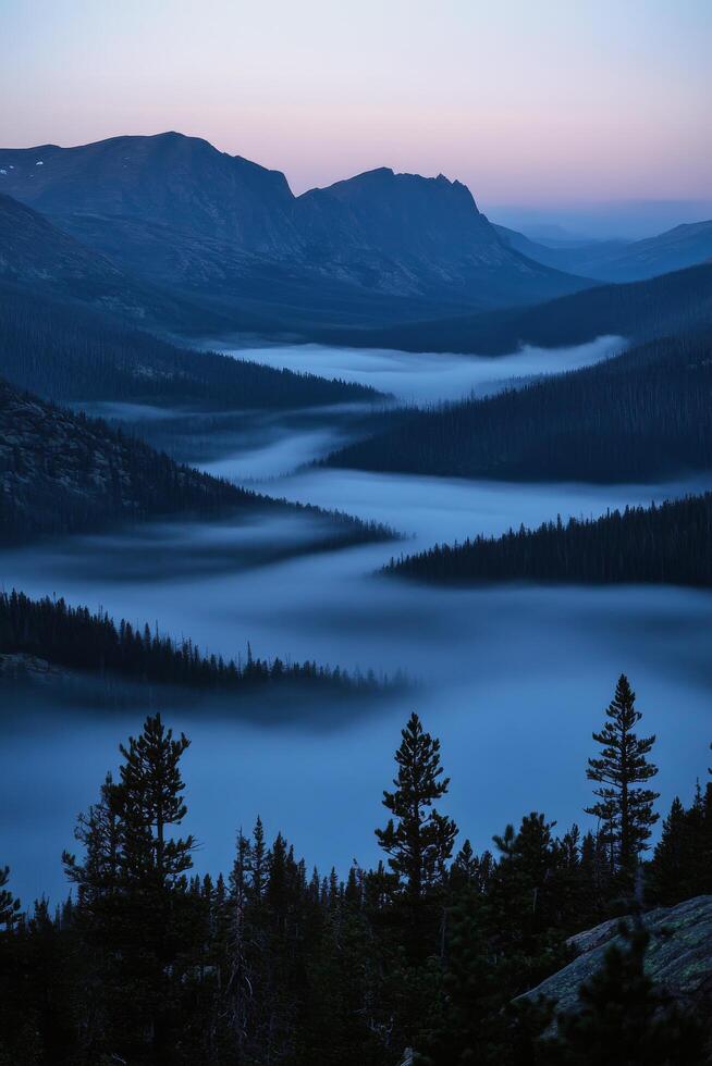 Misty valley landscape at twilight with mountains in the background and dense forest photo