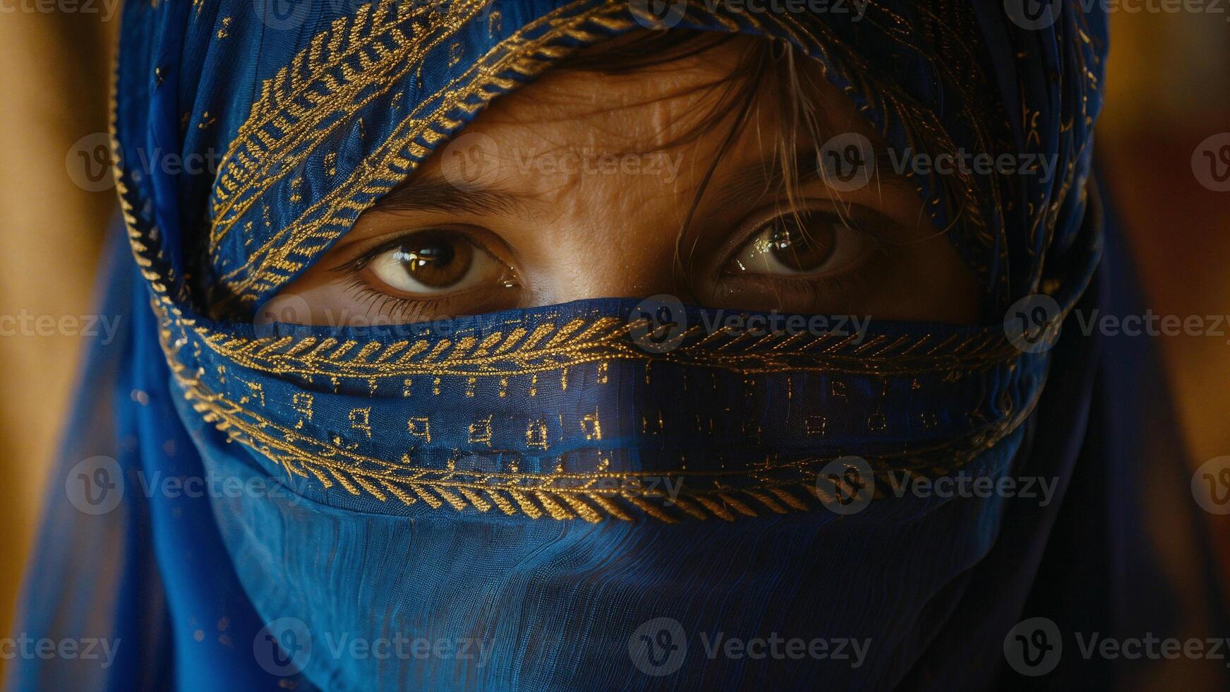 A woman wearing a vibrant blue hijab adorned with intricate gold patterns gazes intensely photo