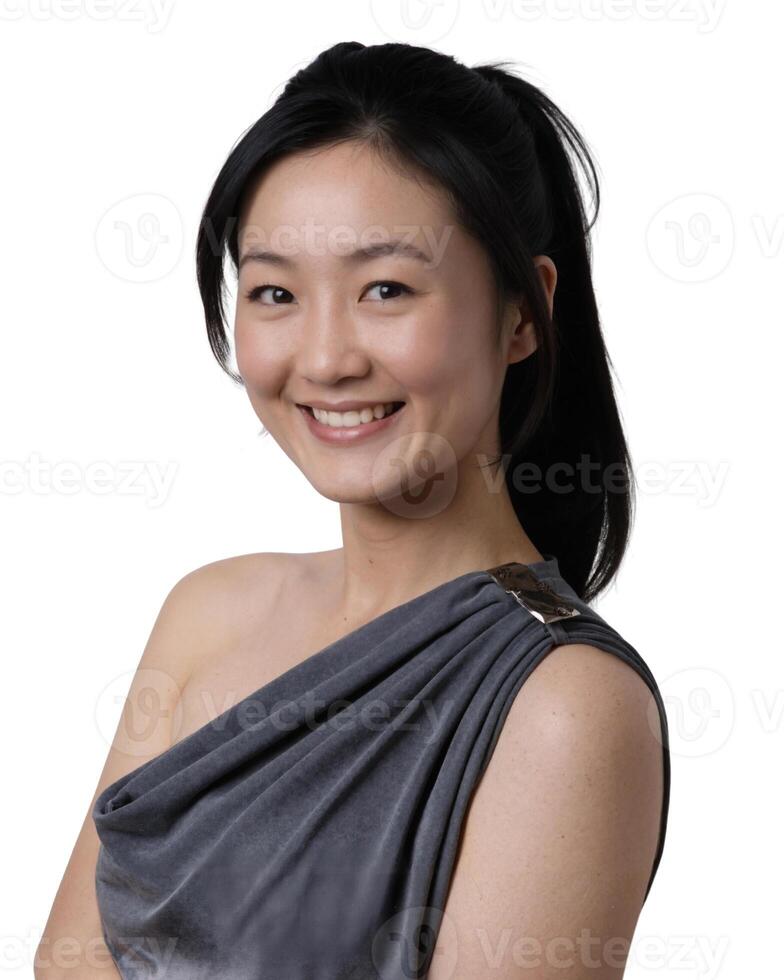 A smiling Asian woman with long black hair, wearing a grey sleeveless top, stands against a white background. photo