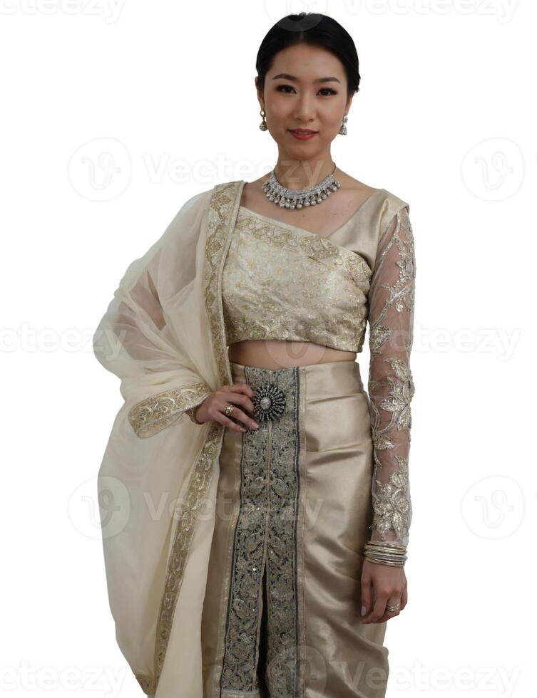 A woman in a beige sari and silver jewelry stands against a plain background, exuding elegance and grace. photo