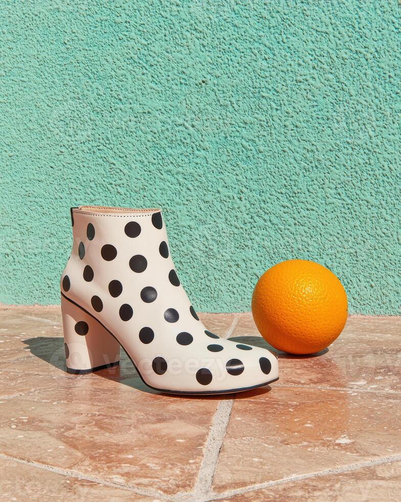 Stylish polka dot ankle boots with block heel against a teal wall photo
