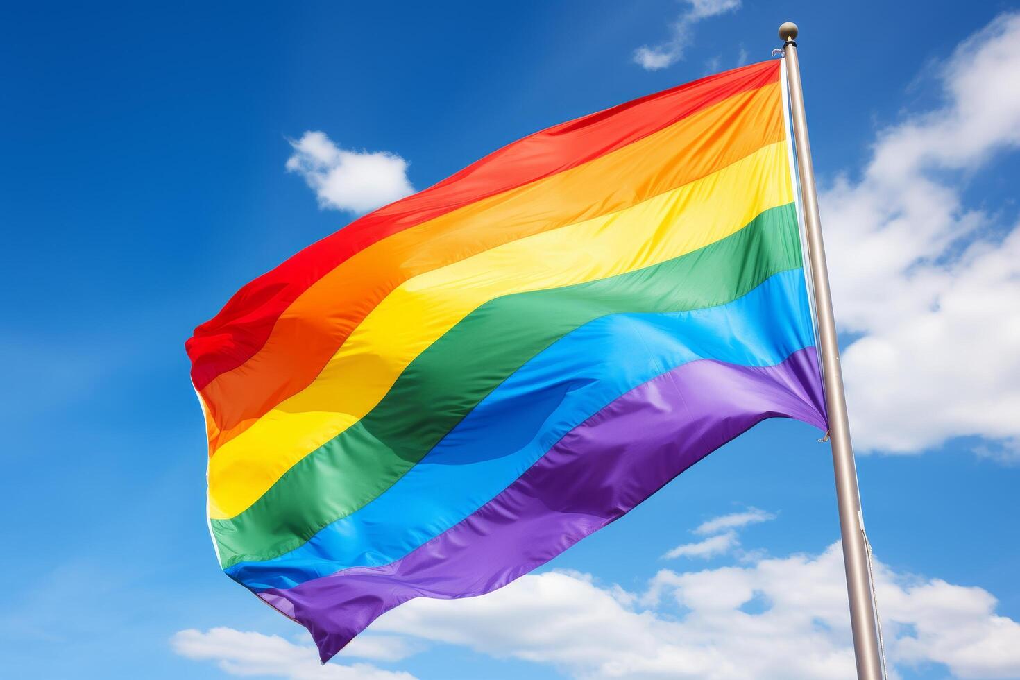 Vibrant rainbow flag waving against a blue sky photo