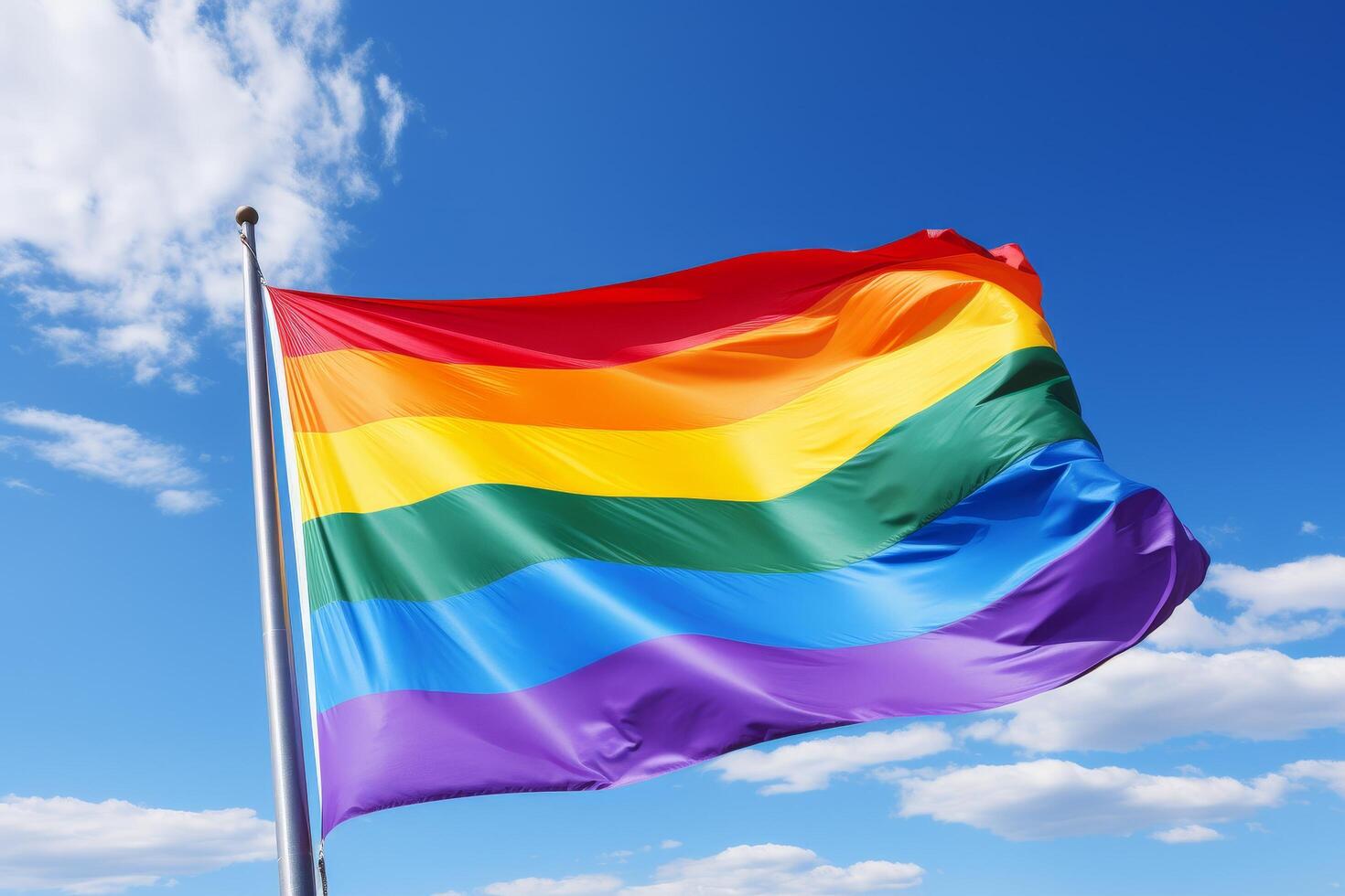 Vibrant rainbow flag waving against blue sky photo
