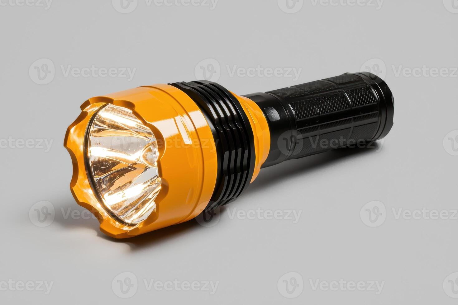 Bright yellow flashlight with a black handle on a gray background photo