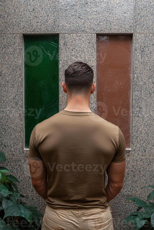 Man standing with his back to the camera in front of a wall photo